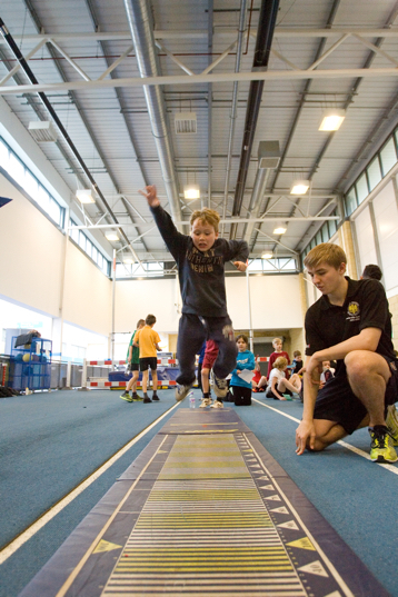 Boy in sports hall taking part in long jump